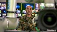 Ein Soldat steht zwischen Fernsehkameras vor zahlreichen Monitoren