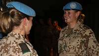 Zwei Soldatinnen stehen sich gegenüber und lächeln, im Hintergrund weitere Soldaten 