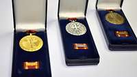 Drei Einsatzmedaillen der Bundeswehr in Gold, Silber und Bronze liegen in Schachteln nebeneinander