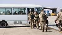 Soldatinnen und Soldaten gehen zu einem Bus, weitere sitzen bereits im Bus 