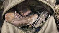 Der Blick in die Kampftragetasche eines Soldaten. Zu sehen ist ein Holster und ein paar Stiefel.