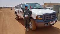 Major Christine Mendy steht in einem afrikanischen Militärcamp für einem Fahrzeug der UN-Truppen. 