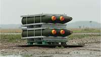 Six bombs lying in a metal rack on a large plate at the range.