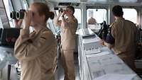 Soldaten der Bundeswehr stehen auf der Brücke eines Schiffes und schauen durch Ferngläser
