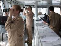 Soldaten der Bundeswehr stehen auf der Brücke eines Schiffes und schauen durch Ferngläser