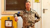 Ein Soldat steht an einem gelben Postkasten