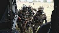 Eine Gruppe Soldaten trägt einen Verwundeten in einem Tragetuch. Sie haben ABC-Schutzmasken auf. 