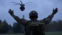 Ein Soldat weist einen Hubschrauber ein. 