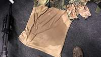 Ein durchgeschwitztes T-Shirt eines Soldaten liegt auf dem Boden. 