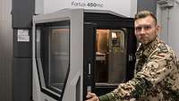 Ein Soldat hält die Luke des 3D-Druckers offen