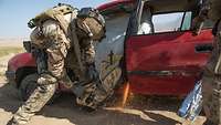 Ein Soldat arbeitet mit einem Trennschleifer, der Funken wirft, an einem Auto