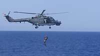 Ein Hubschrauber fliegt dicht über dem Wasser