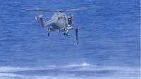 Ein Rettungsschwimmer springt aus einem Hubschrauber ins Meer 