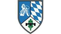 Im silbern-blau geteilten Wappen rechts ein Pionier, links ein Edelweiß, darüber eine Pionierbrücke.