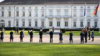 Kramp-Karrenbauer spricht am Rednerpult zu angetretenen Soldaten vor dem Schloss Bellevue