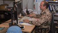 Ein Soldat sitzt am Schreibtisch und arbeitet am Computer