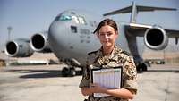 Eine Flugplanerin steht auf dem Rollfeld vor einer Boing C-17 bei der Mission Resolute Support.