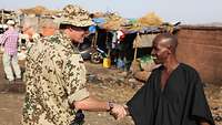 Ein deutscher Soldat schüttelt einem Einheimischen in Bamako die Hand.