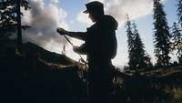 Ein Soldat steht auf einer Bergwiese und hält ein Seil in der Hand.