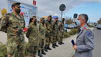 Sechs Soldaten stehen in einer Reihe vor dem Krankenhausparkplatz. Ein Generalstabsarzt spricht zu ihnen.