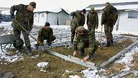 Soldaten bauen eine Unterkonstruktion aus Holz für die geplante Zeltstadt.