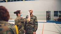 Eine Soldatin führt mit einem Soldaten einen Covid-19-Test in einer Halle durch