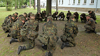  Soldaten sitzen in einem Kreis zusammen.