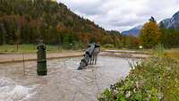 A tube and an excavator arm with gravel in the bucket are sticking out of a water basin. A soldier is standing in the tube.