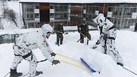 Soldaten schaufeln Schnee von den Dächern.