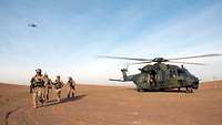 Soldaten laufen vor dem Hubschrauber in der Wüste.