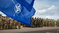 Angetretene Soldaten hinter der NATO-Flagge