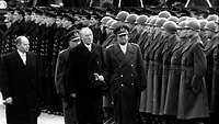 Adenauer und Blank schreiten die Front der angetretenen Soldaten ab (Schwarz-Weiß-Aufnahme)