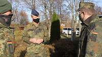 Soldaten im Feldanzug und mit Masken stehen im Freien.