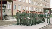 Eine Gruppe von Soldaten in olivfarbener Uniform angetreten vor einem Gebäude