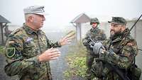 Ein Soldat im Feldanzug spricht in einem Checkpoint mit anderen Soldaten.