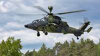 A Tiger attack helicopter flies over trees