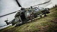 A soldier in motion in front of NH-90 transport helicopter on the ground