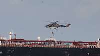Der Hubschrauber steht über dem Deck des Schiffes, an der Winde des Hubschraubers wird ein Soldat heraufgezogen