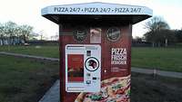 Ein Pizzaautomat steht im Freien vor einer Wiese