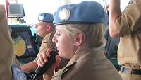 Eine Soldatin sitzt am Arbeitsplatz und hält ein Mikrofon