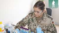 Eine Soldatin sitzt am Labortisch und arbeitet mit Laborausstattung