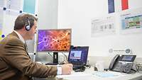 A man is sitting at a desk and consults per computer with his team colleagues