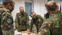 Military personnel of several nations are standing around a table with a map of Europe