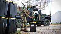 A soldier throws his protective gloves into a medical bin.