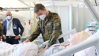 An einem mit einer Puppe belegten Krankenbett steht ein Soldat
