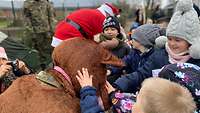 Ein als Rentier verkleideter Soldat lässt sich von den Kindern streicheln.