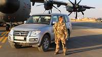 Eine Soldatin steht neben ihrem Einsatzauto vor dem Flugzeug A400M