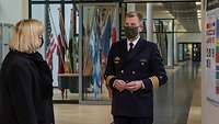 Die Wehrbeauftragte unterhält sich mit Kapitän zur See Gieseler im Flur eines Hörsaalgebäudes