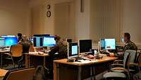 Soldaten sitzen in einem großen Büro an Computerarbeitsplätzen. 