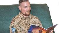 Ein Soldat sitzt auf einem Sofa und liest eine Zeitschrift